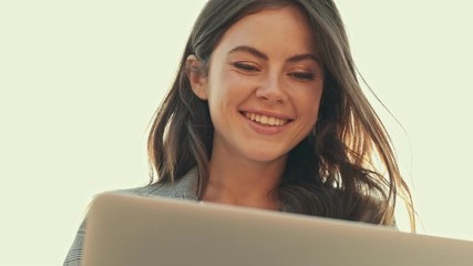 Sticker - Bottom view of happy cute girl is using a laptop outside in the city