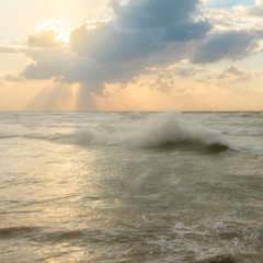 Wall Mural - The rays of the sun breaking through the clouds. Quiet beautiful golden sunset on the sea. Summer nature background.