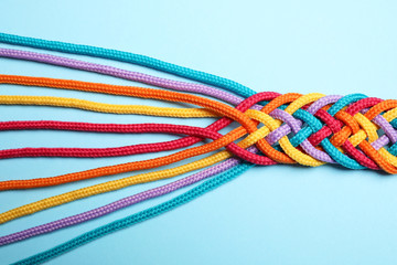 Wall Mural - Braided colorful ropes on light blue background, top view. Unity concept