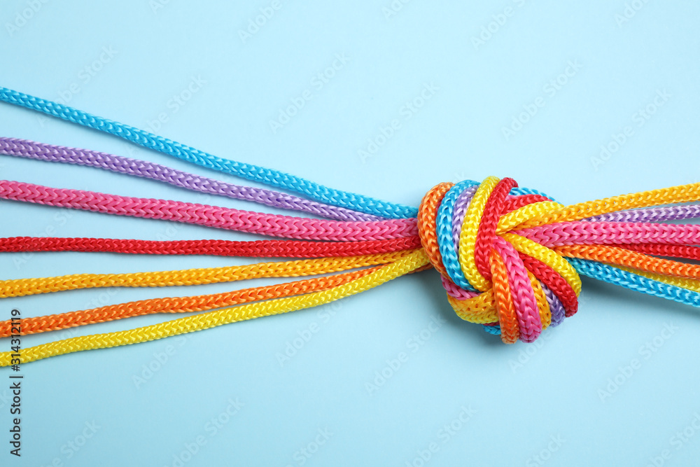 Colorful ropes tied together on light blue background, top view. Unity concept - obrazy, fototapety, plakaty 