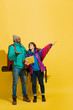 © master1305 - Get agreement in way choosing. Portrait of a cheerful young tourist couple with bags isolated on yellow studio background. Preparing for traveling. Resort, human emotions, vacation, friendship, love.