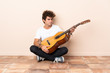 © luismolinero - Young caucasian man with a guitar sitting on the floor with sad expression