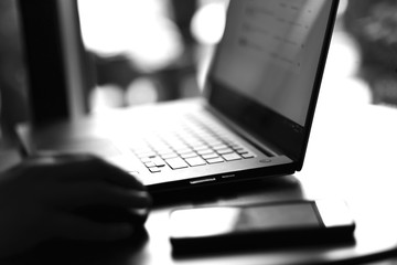 close up view of laptop and mobile phone with freelancer working on it black and white