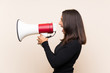 © luismolinero - Young brunette woman with white sweater over isolated background shouting through a megaphone