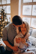 © dimadasha - A guy with a girl is celebrating Christmas. A loving couple enjoys each other on New Year's Eve in a cozy home environment. New Year's love story.