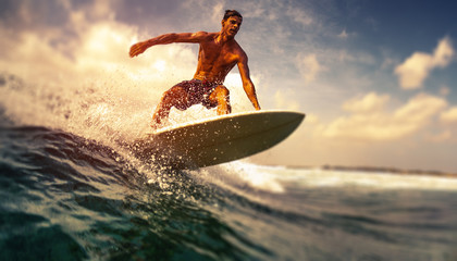 Wall Mural - Surfer rides ocean wave in tropics. Tilt shift effect applied