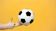 Close Up Female Hold In Hand Palm Soccer Classic White Black Ball, Showing Thumb Up Isolated On Yellow Background. Sport Play Football Healthy Lifestyle Concept. Mock Up Copy Space For Advertisement.