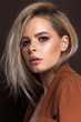 A very beautiful young blonde model with professional make up, perfect skin. Trendy red toned smokey eyes and nude lips.