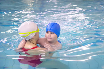 Wall Mural - Little boy learns to swim in an individual lesson with a trainer