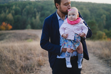 Young happy caucasian man with little baby girl. Parent and daughter walking and having fun together. Father playing with child outdoors. Family, parenthood, childhood, happiness concept.