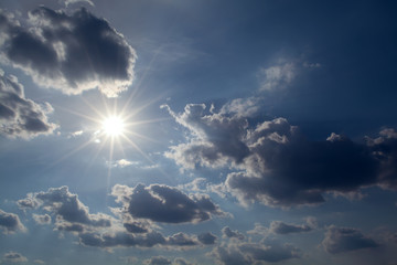 Wall Mural - sun with rays on a background of blue sky with clouds