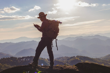 hiker with backpack checks map on smartphone to find directions in wilderness area on top mountain