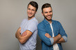 © My Ocean studio - The strength of brothers. Two young men in casual clothes are standing back to back with cheerful facial expressions, posing with folded arms and smiling to the camera.