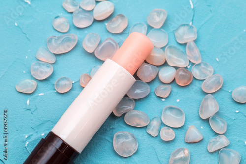 Cuadros en Lienzo Lip balm with rose quartz stones on a turquoise blue background, grapefruit lips