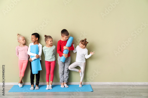 Fotografía Little children with yoga mats near color wall in gym