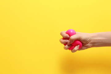 Female hand squeezing stress ball on color background