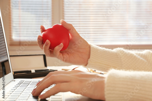 Fotografía Woman squeezing stress ball while working with laptop in office