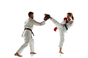 Junior in kimono practicing hand-to-hand combat with coach, martial arts. Young female mongol fighter with green belt training on white studio background. Concept of healthy lifestyle, sport, action.