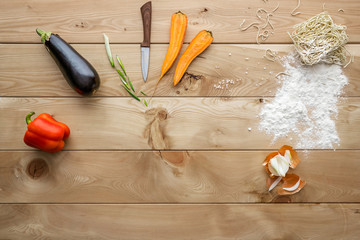 Fresh vegetables, noodles and knife on a wooden table