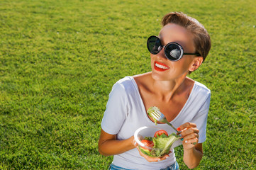 Wall Mural - Beautiful caucasian woman eating salad over green natural background