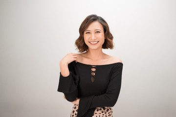 Wall Mural - Happy asian woman in t-shirt posing and looking at the camera over white background