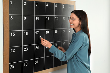 Poster - Young woman writing with chalk on board calendar