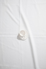 Canvas Print - Top view of clean coffee cup on white cloth with copy space