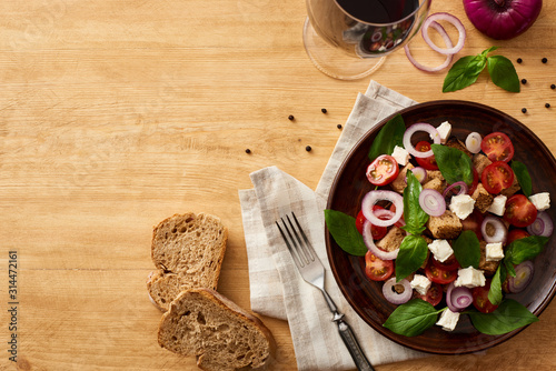 Fotografía top view of delicious Italian vegetable salad panzanella served on plate on wood