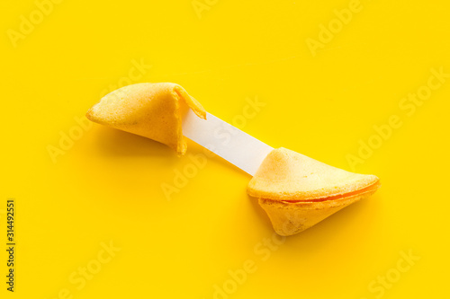 Fotografía Fortune cookie - broken piece with prediction inside - on yellow background copy