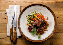 Grilled Venison Ribs With Baked Vegetables And Berry Sauce On Wooden Background