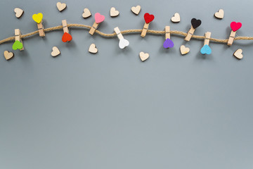 Wall Mural - Colorful clothespins in the form of hearts on a rope. Decoration for Valentine's day. Decorative clothespins on a gray background