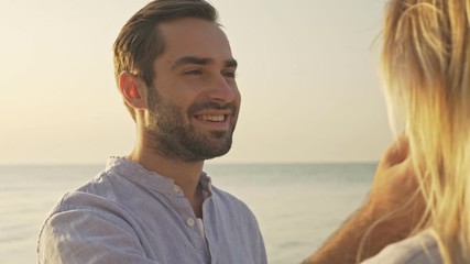 Wall Mural - Handsome lovely young man is admiring a nice woman at the beach at the dawn