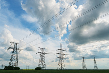 Electrical net of poles on a panorama of blue sky and green meadow