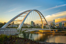 Edmonton, Alberta, Canada Skyline At Dusk With Suspension Bridge In Foreground And Clouds
