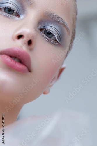 Fotografía Artistic close up photo of a girl with blue eyes and winter make-up, snowy eyelashes and eyebrows