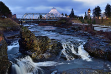 Long Exposure, Sunrise Photo Of Spokane Falls On The Spokane River Looking Over Riverfront Park In Downtown Spokane, Washington With A Clock Tower, Bridge And Pavilion In The Background