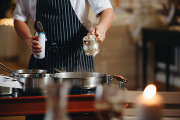 The chef prepares food in front of the visitors in the restaurant close up.