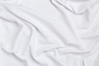 White crumpled bedding sheets. Texture fabric. Cozy background. Flat lay, top view.
