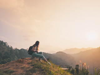 Wall Mural - hipster girl with backpack enjoying sunset on hill. solo traveling, happiness emotion, summer holiday concept