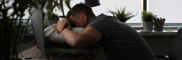 Man sleeping on office table evening time background. Man wants to go home and lives at work. Overtime night work concept.