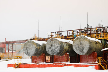 Wall Mural - Large horizontal shell-and-tube tanks heat exchangers with liquid at an industrial petroleum refining petrochemical chemical plant in the snow in winter