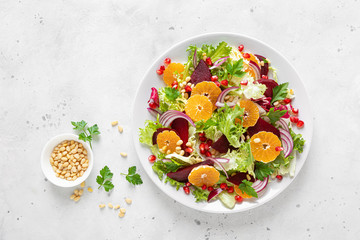 Christmas salad with boiled beet, red onion, tangerines, pomegranate, parsley, pine nuts and lettuce leaves