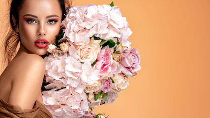 Wall Mural - beautiful white girl with flowers. stunning brunette girl with big bouquet flowers of roses. closeup