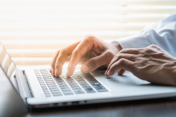 Businessman typing on laptop keyboard and one hand on touchpad. Business concept.