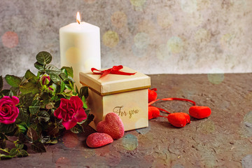 Canvas Print - St. Valentine's Day card. Gift box with bow, roses, burning candle, candy hearts on a dark stone background, copy space.