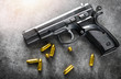 © Milan - Detail of 9mm pistol, bullets and handcuffs. Gun with ammunition on dark stone background.
