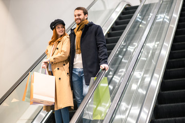 caucasian redhaired woman and bearded man smile, enjoy shopping together, happ after buying new clot