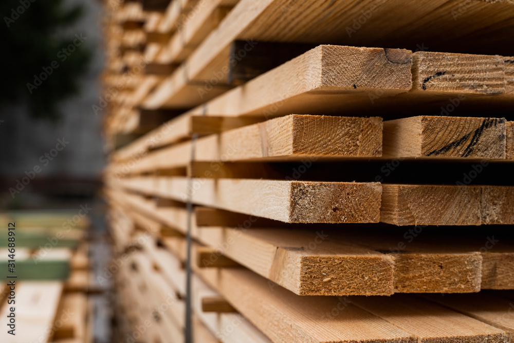 Piles of wooden boards in the sawmill, planking. Warehouse for sawing boards on a sawmill outdoors. Wood timber stack of wooden blanks construction material. Industry. - obrazy, fototapety, plakaty 
