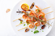 © Artem Kudryavtsev - grilled shrimp on skewers. Grilled seafood on skewers with spices, herbs and lemon. delicious prawn. White plate. White background