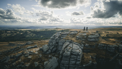 A drone shot of two people standing on the rocky hill in Dartmoor country park